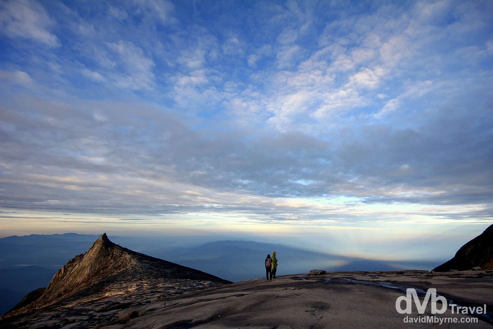 A picture captured on the descent of climbers admiring the post sunrise view over Sabah, Malaysian Borneo, from the granite expanse leading to the summit of Mount Kinabalu. The views of Sabah from this height, stretching out below in all directions, are phenomenal. June 23rd 2012.