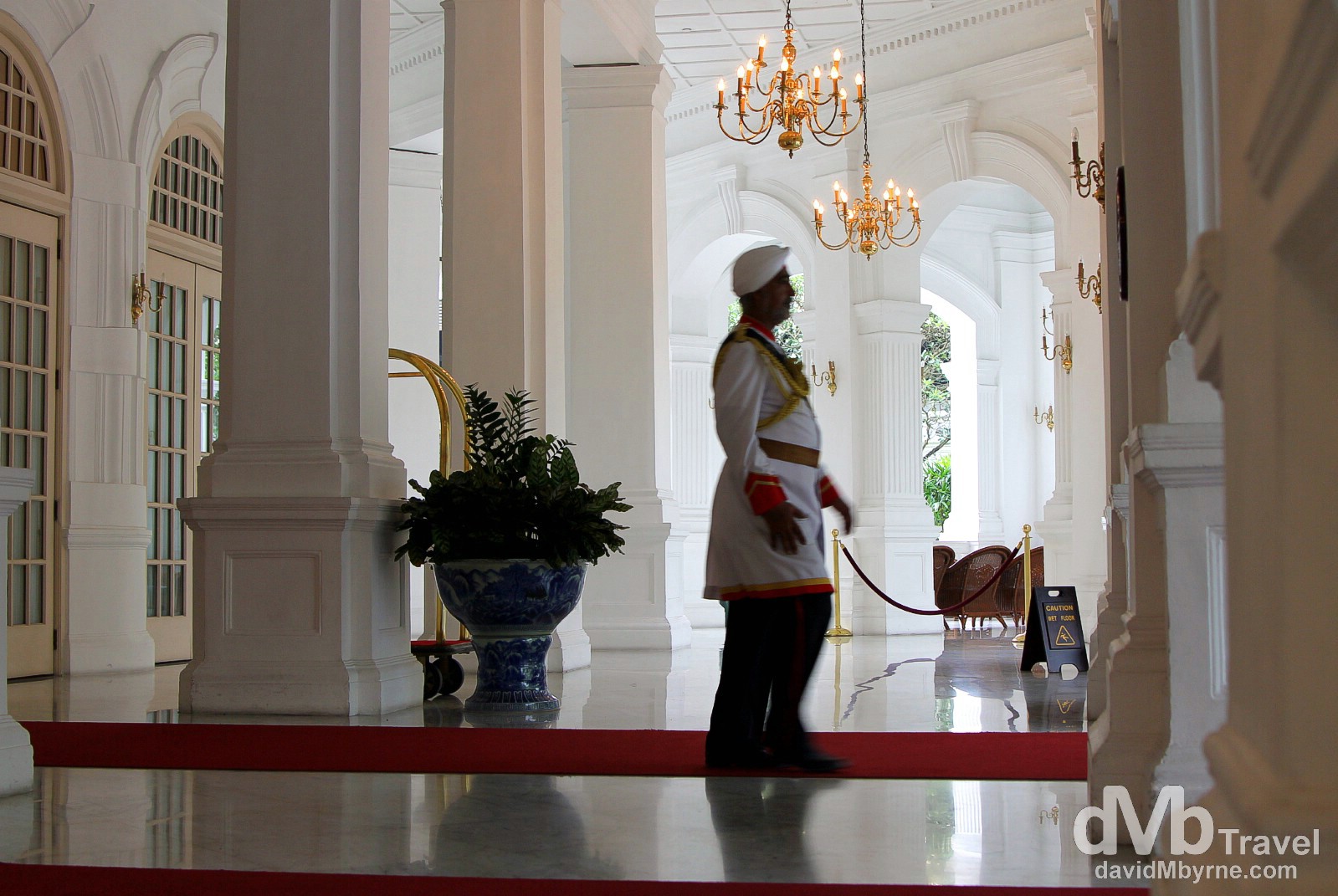 A doorman at the lobby entrance to Raffles Hotel, Singapore. A Singaporean institution & colonial opulence personified, the regal Raffles Hotel opened as a modest 10-room bungalow in 1887 with the main building following in 1889. By the 1970's it had seen better days & was a shabby relic of its old, glamorous self. A major revamp in time for a 1991 reopening brought it back to something resembling its former glory. I spent an hour or so sniffing around and sticking my camera at white walls, arches, fancy gold chandeliers, polished marble floors, & rich people. It was fun. Raffles Hotel, Singapore. March 28th 2012.