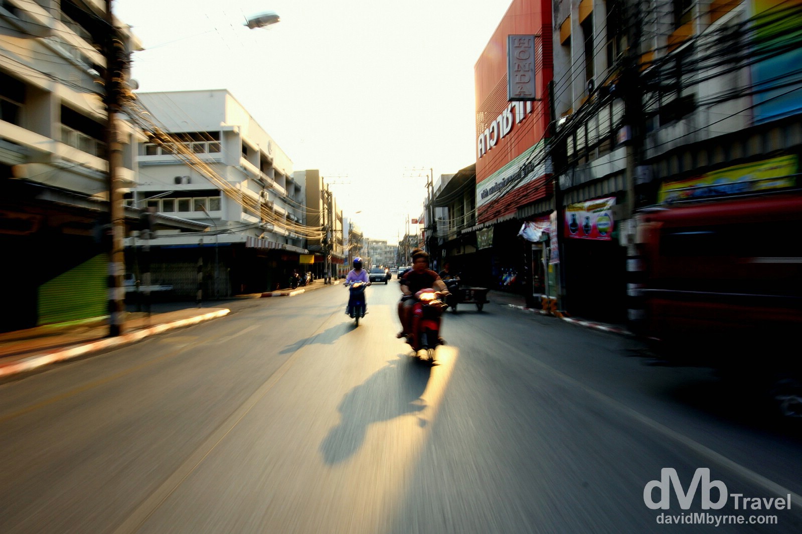 Motion & late afternoon shadows as seen from the back of a moving sawngthaew, an open-backed pick-up that doubles as a taxi, on the way to the Chiang Mai bus station to get the bus to Bangkok. March 15th 2012. on the streets of Chiang Mai, northern Thailand. March 15th 2012 