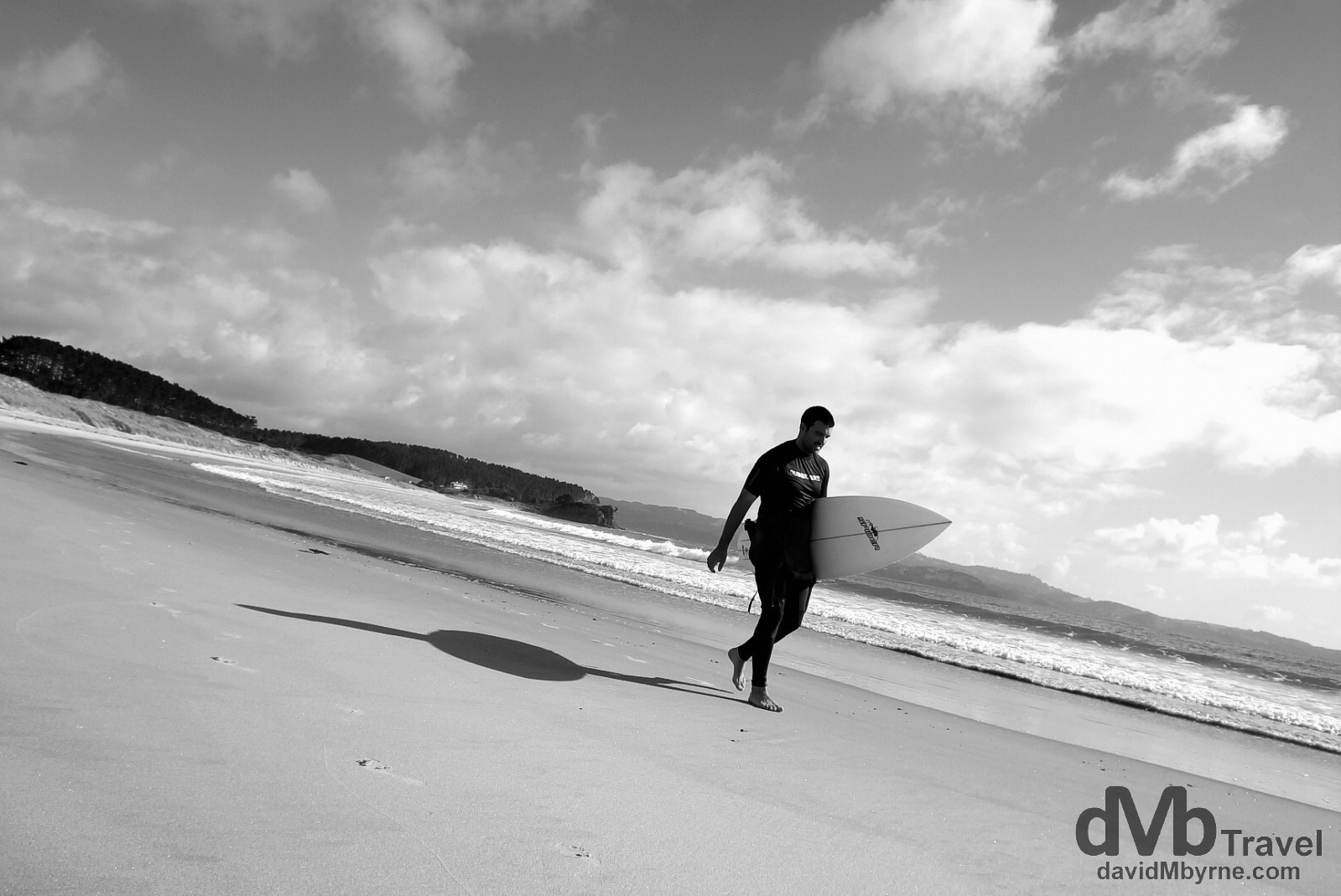 A surfer walking on the beach in Tawharanui Regional Park, North Island, New Zealand. April 28th 2012.