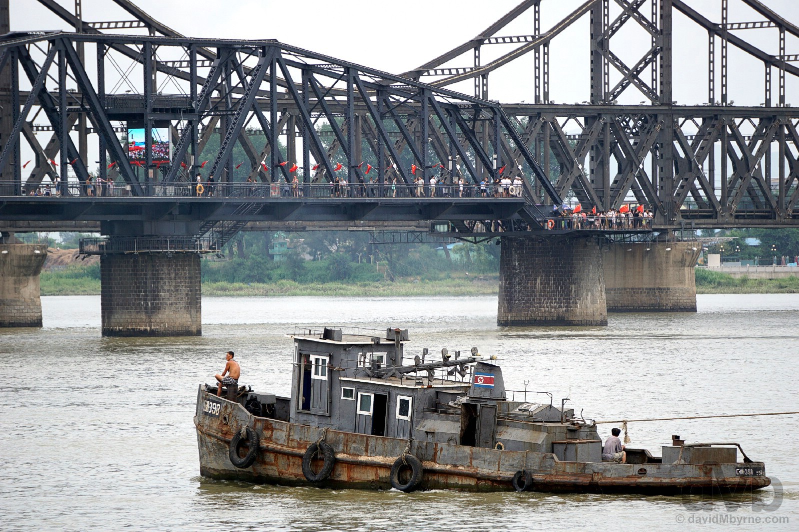 A North Korean-registered tug boat plies the Yalu River with the Broken Bridge in the background as seen from Dandong, Liaoning province, China. August 13, 2017.